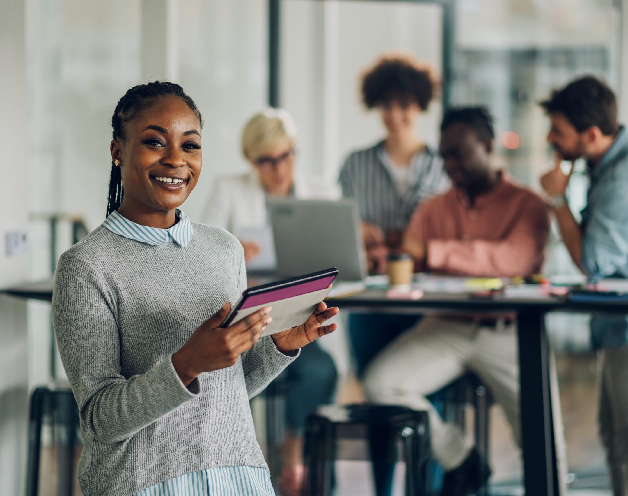 Black business woman standing in a office with colleagues in the