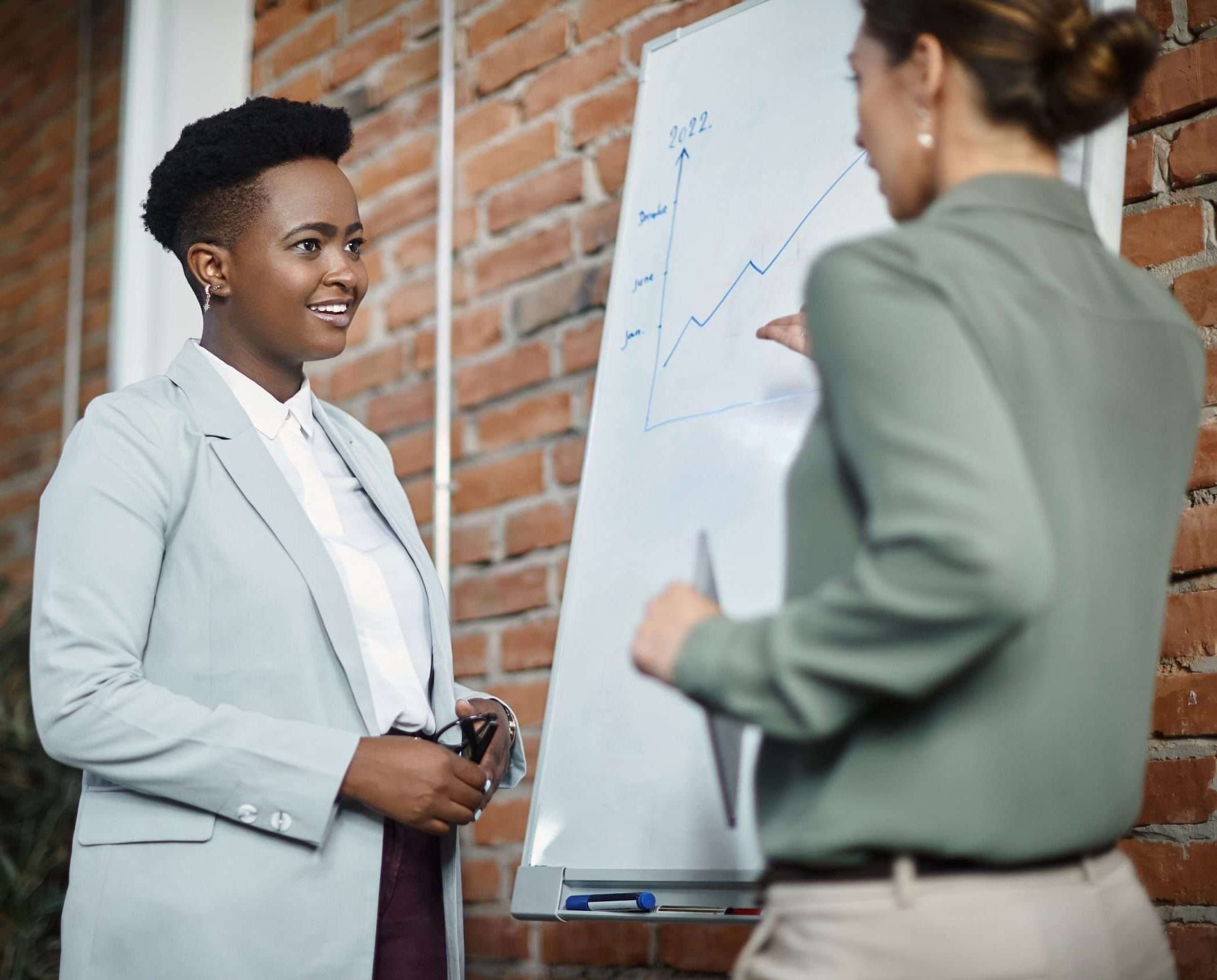 Happy black businesswoman and her colleague brainstorming during presentation at meeting room.