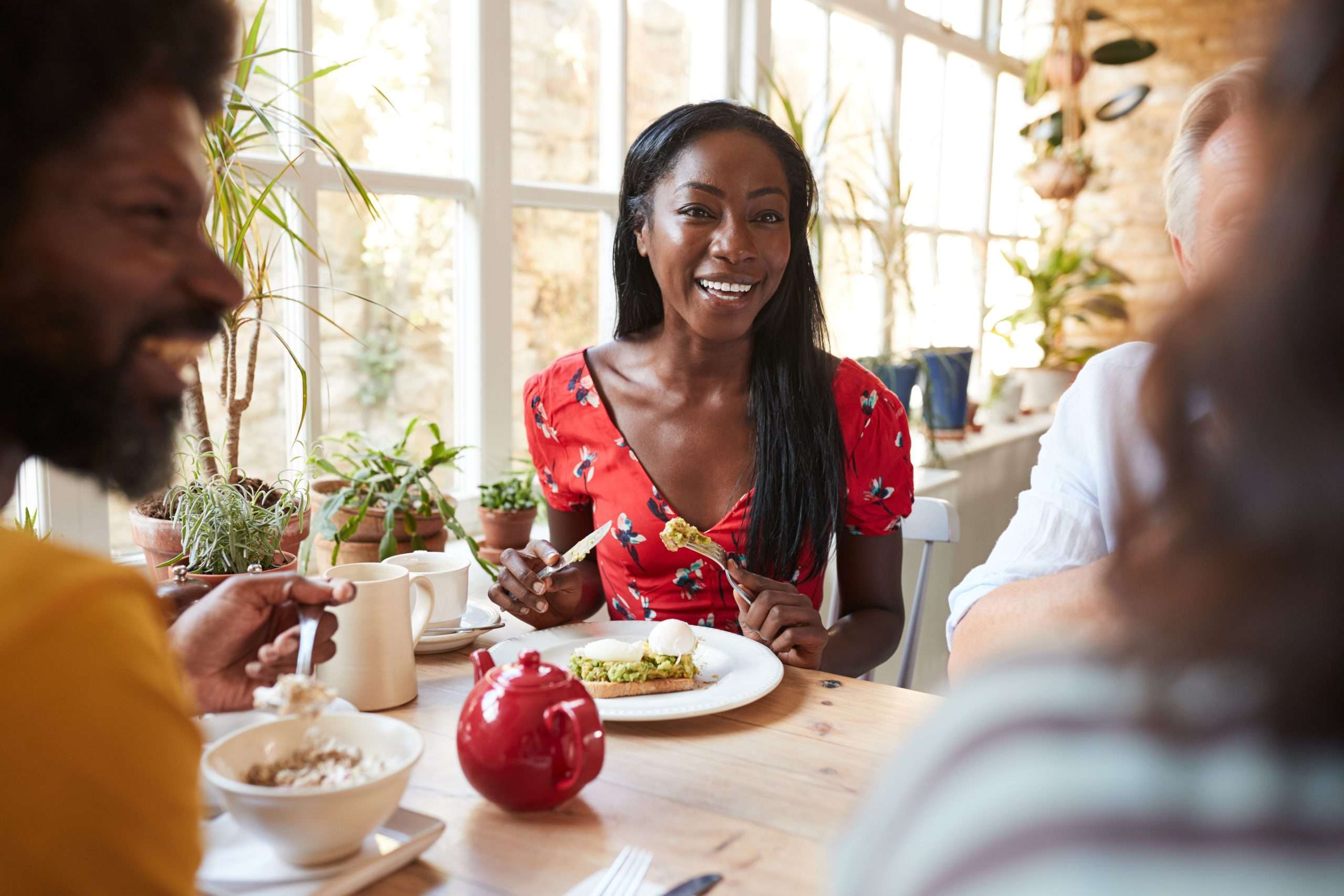Happy young black woman eating brunch with friends at a cafe