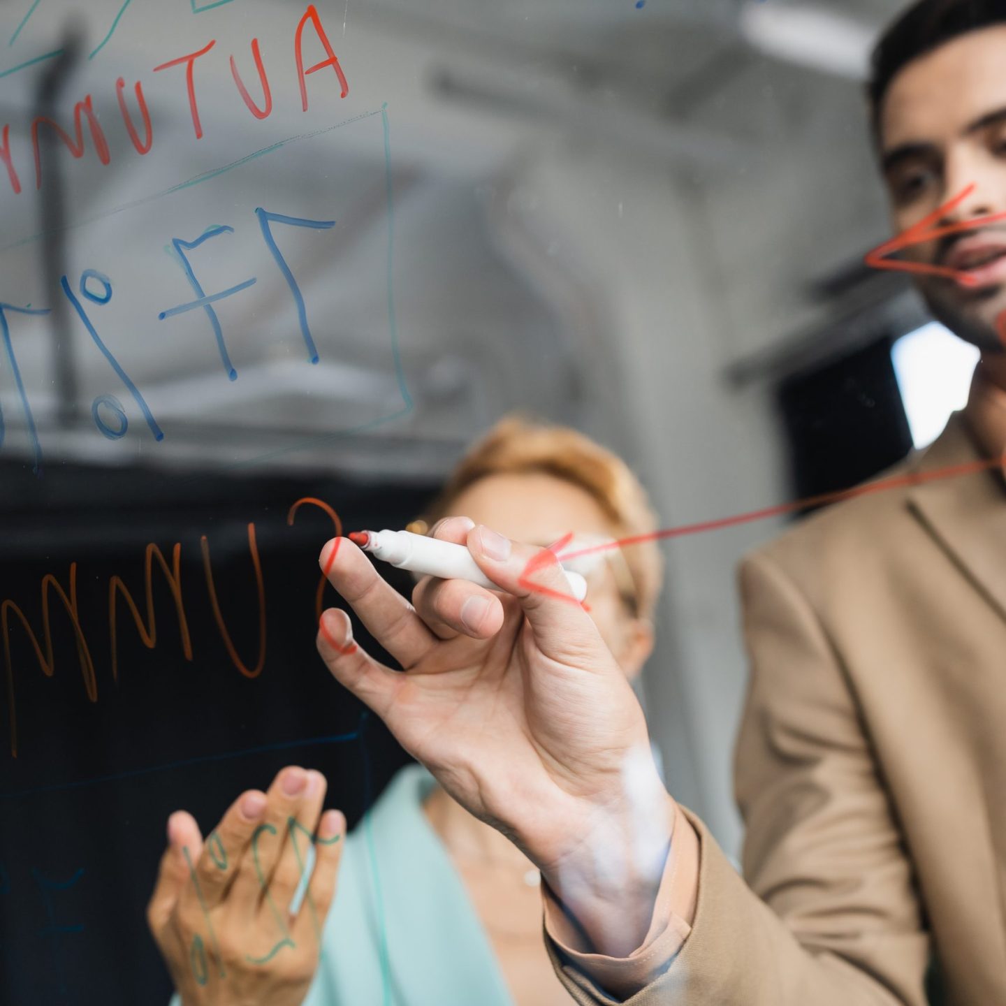blurred businessman with felt pen writing on clipboard near woman pointing with hand in office