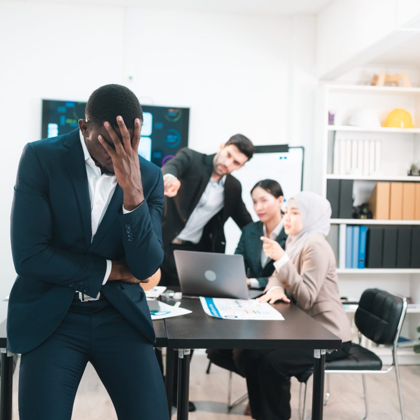 Frustrated African American businessman stressed and overwhelmed in meeting room after facing business problems with diverse team, business failure, corporate pressure, financial difficulties.
