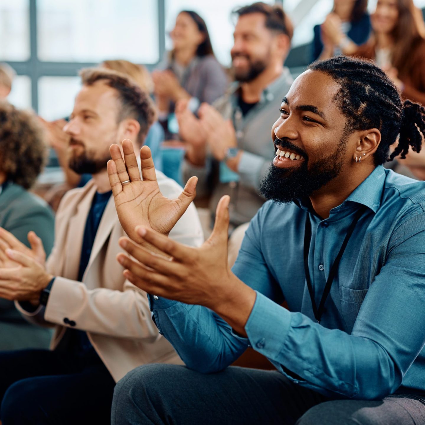 Happy African American entrepreneur applauding while attending business seminar at conference hall.