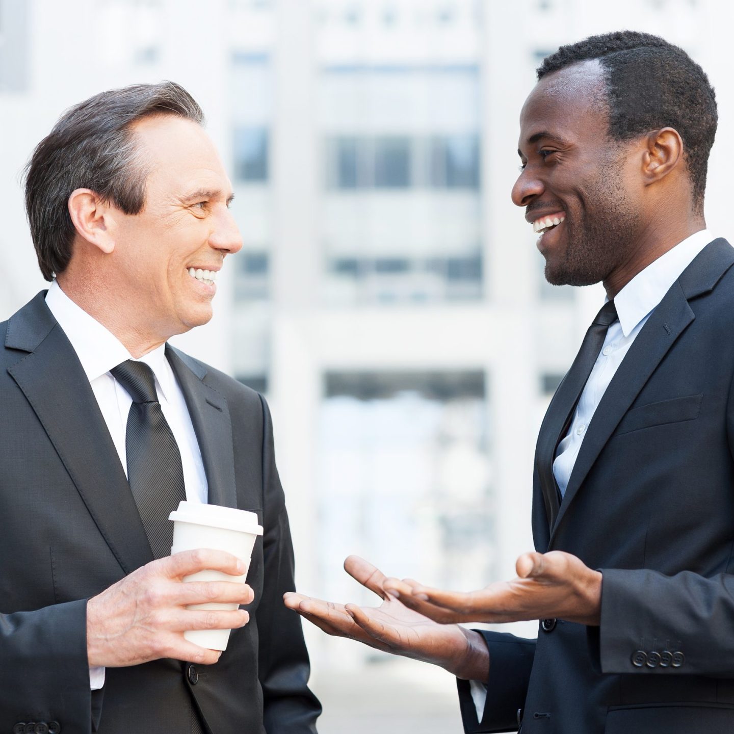 Having a break to talk around. Two cheerful business men talking and gesturing while standing outdoors