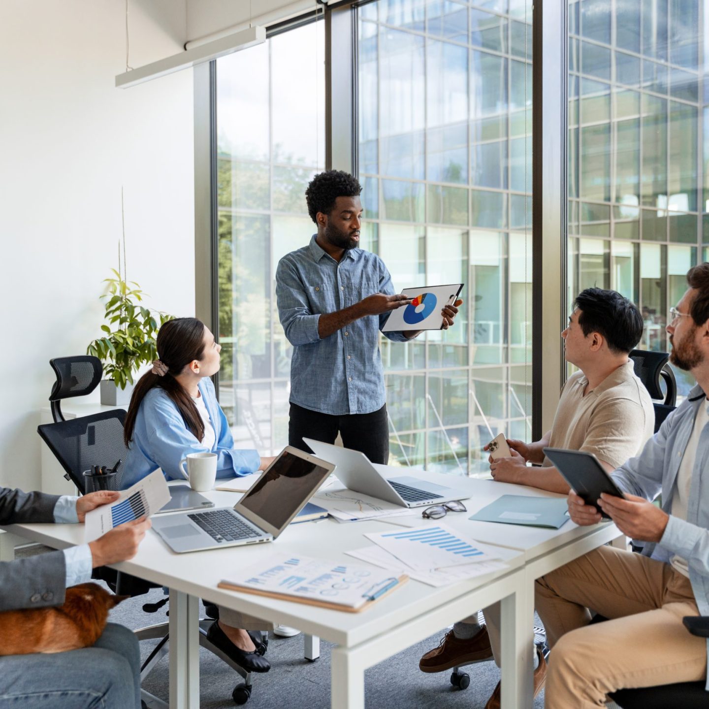 Marketing manager presenting a pie chart during a corporate meeting, engaging a diverse team in discussion and strategy development