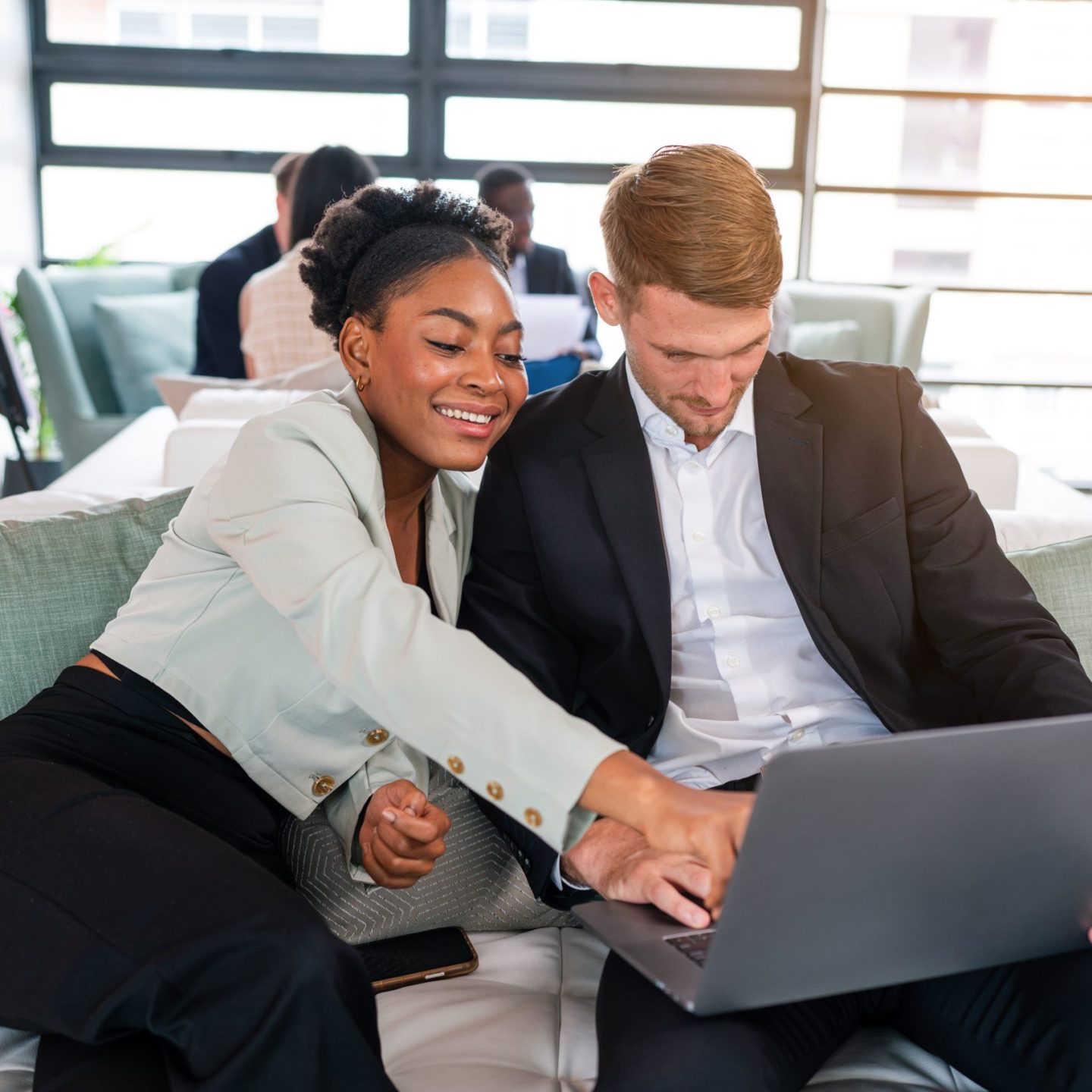 Two happy business woman and man using laptop working on computer at workplace. Cheerful young professional multiethnic colleagues team discussing online digital technology corporate project in office