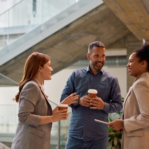 Multiracial group of business coworkers having a coffee break in the office. Happy businessman talking to his female colleagues during their coffee break at work.